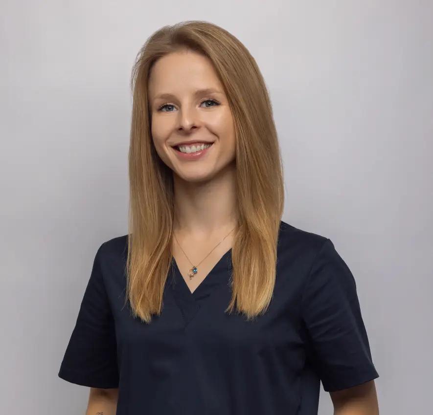 Uśmiechnięta blondynka w ciemnym uniformie na szarym tle