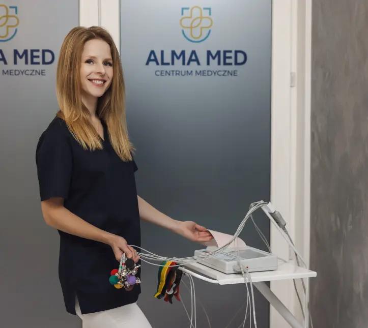 Uśmiechnięta blondynka w uniformie, która przygotowuje w gabinecie badanie EKG.